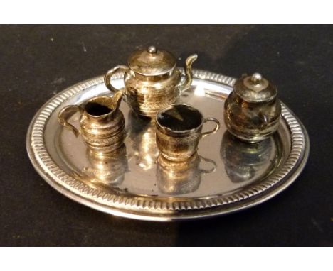 A White Metal Miniature Tea Service comprising of teapot, cream jug, sucrier and mug upon an oval tray