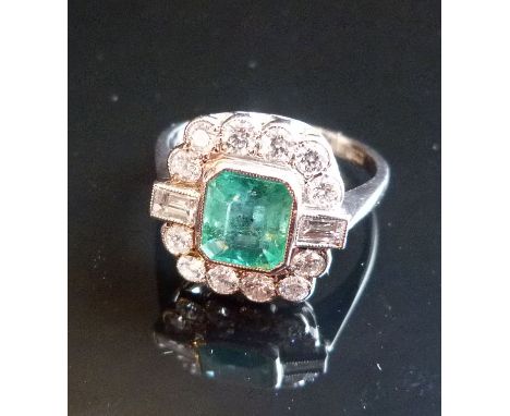 An 18ct. White Gold Emerald and Diamond Ring, the large rectangular central emerald surrounded by diamonds and with baguette 