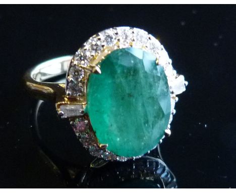 An 18ct. Yellow Gold Emerald and Diamond Ring, the large central oval emerald surrounded by diamonds and with diamond shoulde