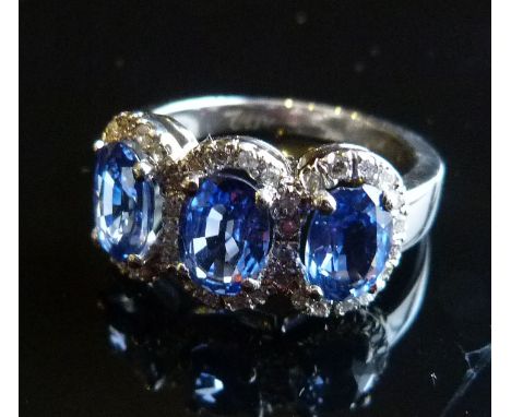 A Platinum Three Stone Sapphire and Diamond Ring, set with three oval sapphires surrounded by diamonds within a pierced setti