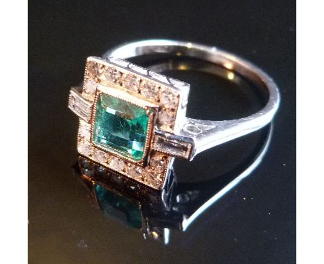 An 18ct. White Gold Emerald and Diamond Ring, with large central emerald surrounded by diamonds and with baguette diamond sho