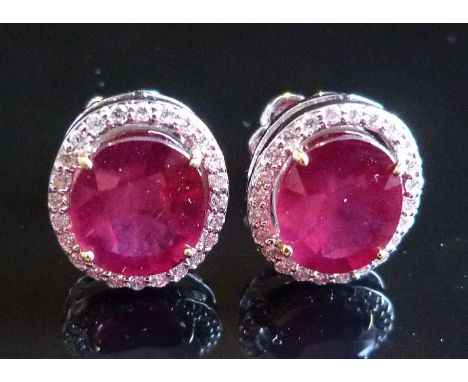 A Pair of 18ct. White Gold Ruby and Diamond Cluster Ear Studs with Central Oval Rubies surrounded by Diamonds, approximately 