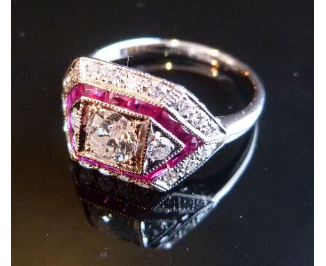 An 18ct. White Gold Ruby and Diamond Ring in the Art Deco Style, with three central diamonds surrounded by a band of rubies a