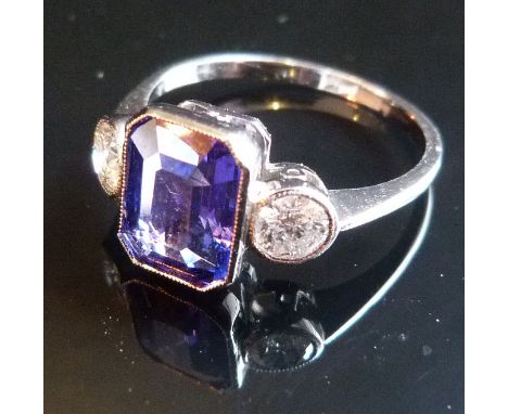 An 18ct. White Gold Tanzanite and Diamond Three Stone Ring, the large central tanzanite opposed by two diamonds within a pier