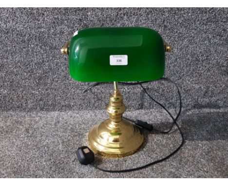 A brass library lamp with green glass shade.