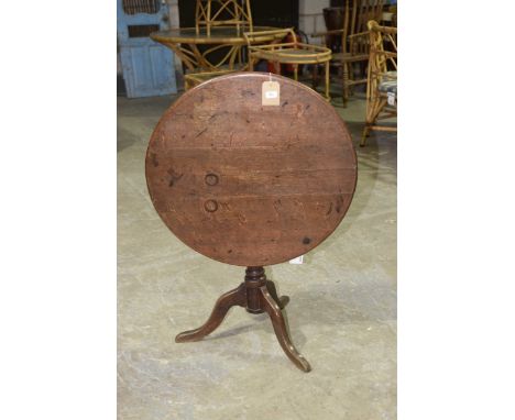 A Georgian oak tripod tableHaving a circular plank top supported on a ring turned baluster shaft with three downswept support