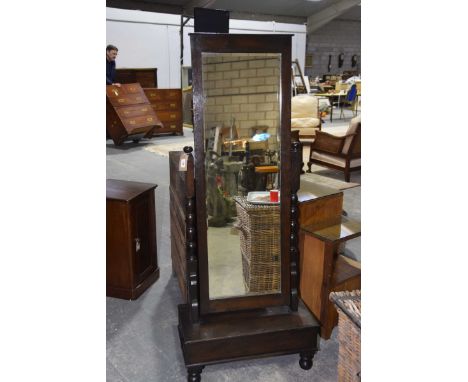 A 1920's oak cheval mirror The rectangular bevelled mirrored plate supported on bobbin turned uprights above a plinth base wi