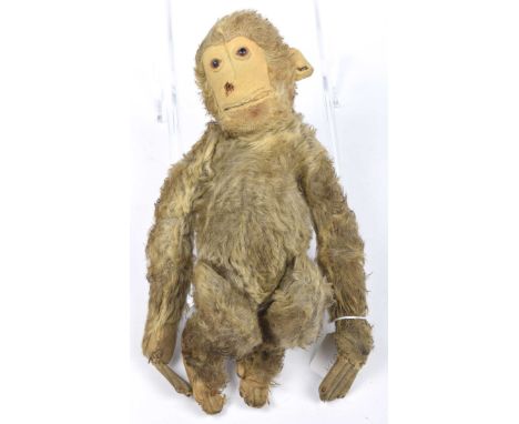 A Steiff brown plush monkeyWith glass eyes, felt face, ears, hands and feet, with pin to left ear, height 33cm. 