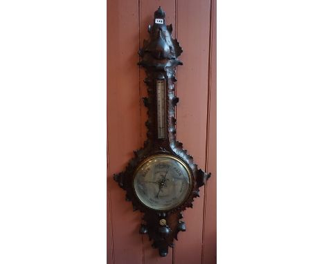 A Black Forest Carved Wall Barometer, circa early 19th century, with a silvered thermometer guage above a silvered dial, sign