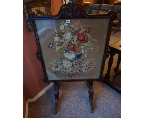 A William IV Rosewood Firescreen, With a floral decorated tapestry panel, raised on scroll supports with brass castors, 116cm