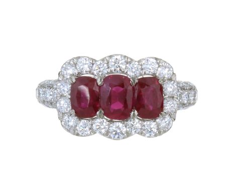 A BURMA NO HEAT RUBY AND DIAMOND DRESS RING in platinum set with three graduated oval cut rubies totalling 2.20 carats surrou