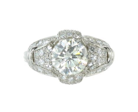 A DIAMOND COCKTAIL RING in platinum set with a central round cut diamond of 3.52 carats within a jewelled scrolling mount set