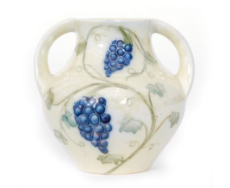 William Moorcroft - A miniature twin handled vase decorated in the Grape pattern with tubelined vines and fruits against a ye