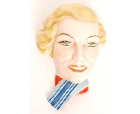In the manner of Royal Dux - A 1930s Art Deco face mask modelled as a blonde haired lady wearing a blue and red scarf, printe