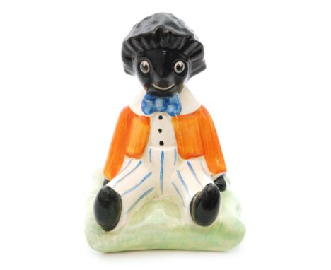 Clarice Cliff - Golly - A novelty figure of a seated Golly circa 1930 in orange jacket and striped trousers seated to a green