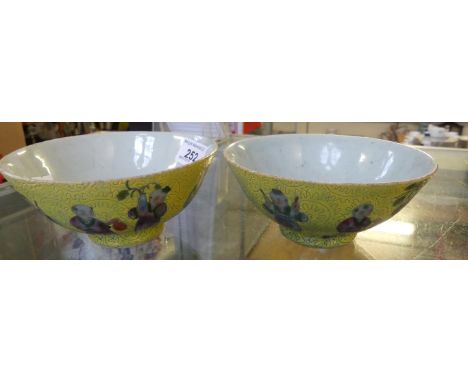A pair of small Chinese pedestal bowls decorated with figures on a yellow background, seal mark to base.