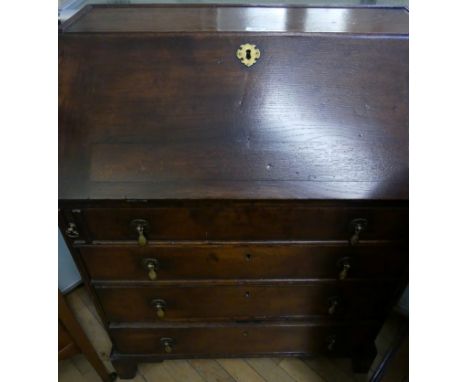A Georgian style oak bureau of small proportions, the hinged cover enclosing fitted compartment and secret panel, above four 