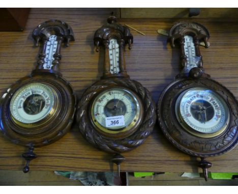A collection of three early 20th Century aneroid barometer/thermometer combinations in carved banjo shaped wooden frames.  