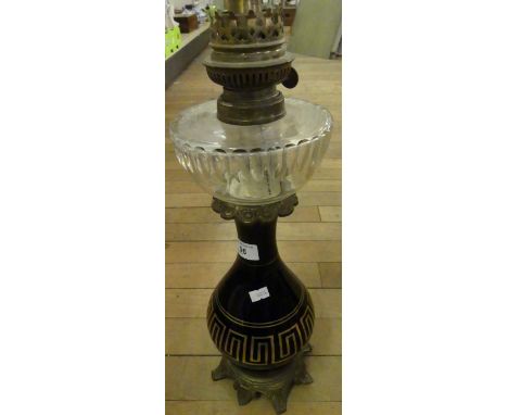 A late 19th/early 20th Century oil lamp with clear glass font and black glass base, decorated in a Greek key design.