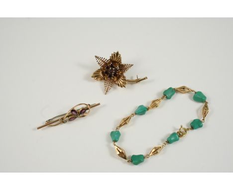 A 9CT. GOLD AND GARNET FLOWER BROOCH the gold flowerhead is centred with seven circular-cut garnets, 4.5cm. long, together wi