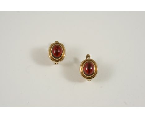 A PAIR OF GOLD AND GARNET EARRINGS each set with an oval-shaped cabochon garnet within a 9ct. gold surround, 1.5cm. long.