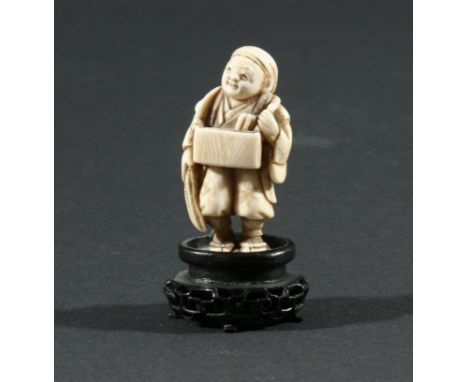 TWO JAPANESE NETSUKE, the first of a man standing with a box hung from his neck, height 5.2cm, together with another carved a