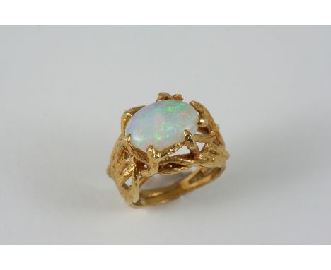 AN OPAL AND GOLD RING the oval-shaped solid white opal is set within an 18ct. gold abstract design setting. Size L.