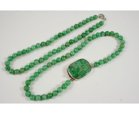A SINGLE ROW UNIFORM JADE BEAD NECKLACE the beads measure approximately 8.4mm. and are set to a pierced and carved jade clasp