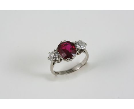 A RUBY AND DIAMOND THREE STONE RING the oval-shaped ruby is set with two old brilliant-cut diamonds, in 18ct. white gold. Siz