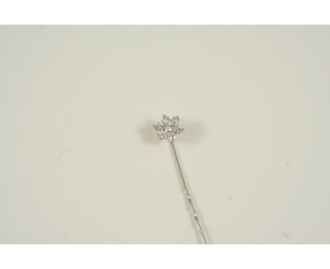 A DIAMOND SET STICK PIN of flowerhead form, centred with a brilliant-cut diamond within a surround of six smaller brilliant-c