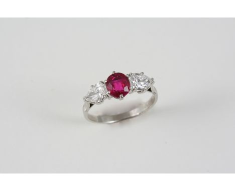 A RUBY AND DIAMOND THREE STONE RING the oval-shaped ruby is set with a pear-shaped diamond to each shoulder, in platinum. Siz