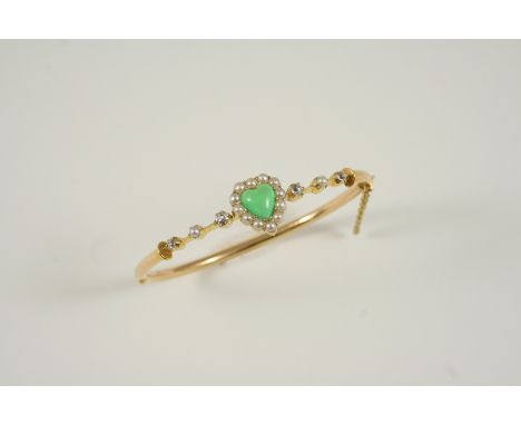 A LATE 19TH CENTURY GOLD HALF HINGED BANGLE mounted with a heart-shaped chrysoprase within a surround of half pearls, with ro