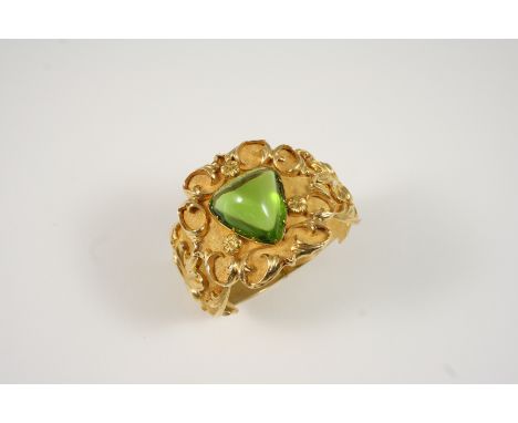 A VICTORIAN GOLD AND PERIDOT HINGED BANGLE the gold bangle with embossed foliate decoration is centred with a rounded triangu