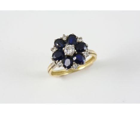 A SAPPHIRE AND DIAMOND CLUSTER RING centred with a circular-cut diamond within a surround of oval-shaped sapphires and small 