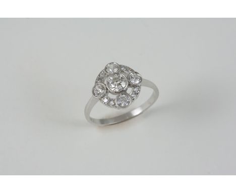 A DIAMOND CLUSTER RING centred with a circular-cut diamond within a surround of four circular-cut diamonds and eight smaller 