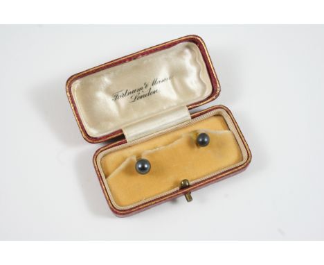 A CASED SET OF TWO GOLD AND BLACK PEARL DRESS STUDS in fitted case by Fortnum & Mason, London.