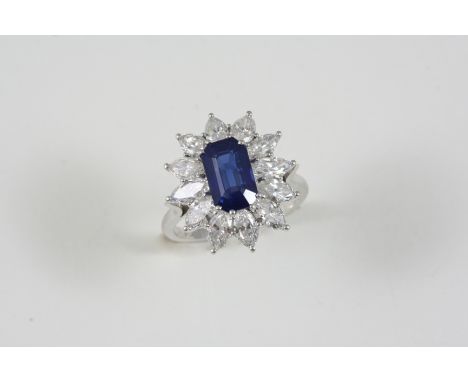 A SAPPHIRE AND DIAMOND CLUSTER RING the sapphire is set within a surround of twelve marquise-cut diamonds, in platinum. Size 