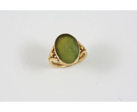 A HARDSTONE SET SIGNET RING the nephrite jade is engraved with a warrior and set in gold mount and shank. Size H.