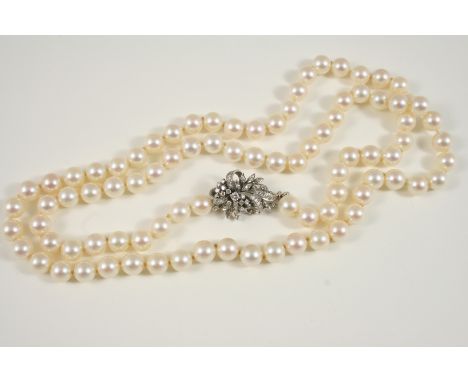 A UNIFORM SINGLE ROW CULTURED PEARL NECKLACE the pearls measure approximately 8.0mm., and are set to a foliate and bow diamon