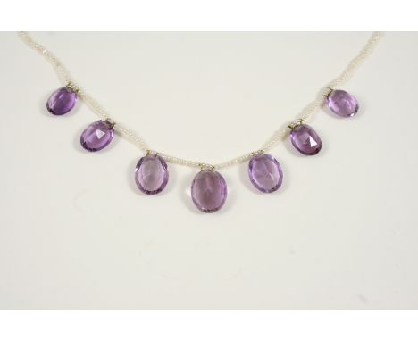 AN AMETHYST AND SEED PEARL NECKLACE the seed pearl necklace suspends seven graduated oval-shaped amethyst drops, 42cm. long.