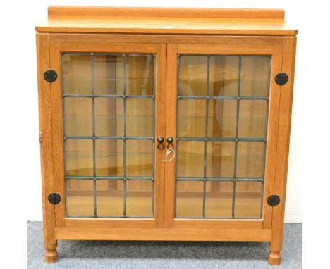 A Robert ''Mouseman'' Thompson Oak Display Cupboard, with raised upstand, above two leaded glazed doors enclosing three glass
