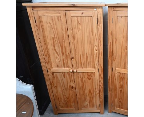 A modern pine wardrobe with a pair of full-length panelled doors enclosing a hanging rail beneath a single shelf, 186 cm high