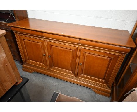 A large teak sideboard with three cushion moulded drawers over panelled cupboards, raised on bracket feet (a/f), side panel d