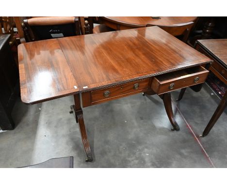 A Regency style mahogany and ebony strung sofa table with drop leaf top and two frieze drawers on supports with reeded splaye
