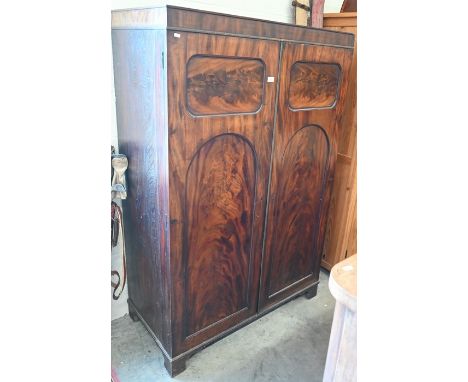A 19th century flame mahogany hall cupboard, two full length panelled doors enclosing hanging rail, raised on bracket feet,, 