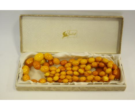 A double strand of graduated butterscotch amber beads 9ct. gold fastening, 73cm long; a similar pair of pearl drop earrings, 