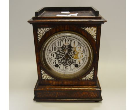 An early 20th Century oak mantel time piece, illustrated spandrels and dial
