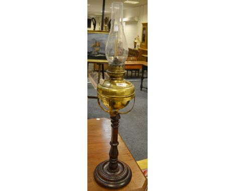 A Victorian brass and oak oil lamp, brass reservoir, turned oak column and foot.