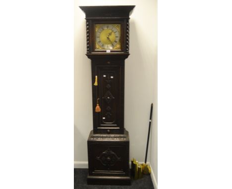 An early 20th Century oak longcase clock, carved to frieze, barley twist pilaster enclosing brass dial decorated in putti spa