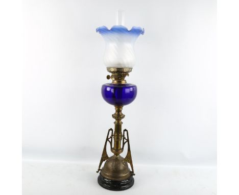 An Art Neuveau oil lamp with blue glass well and shade, height 76cmsome wear to metal surfaces, worn through in places. Shade